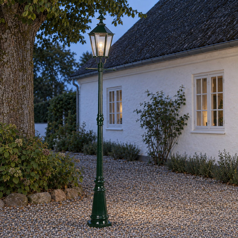 Manchester standerlampe, m/ K7b, Hjd. 228 m monteret ved et dansk hus i aftenlys
